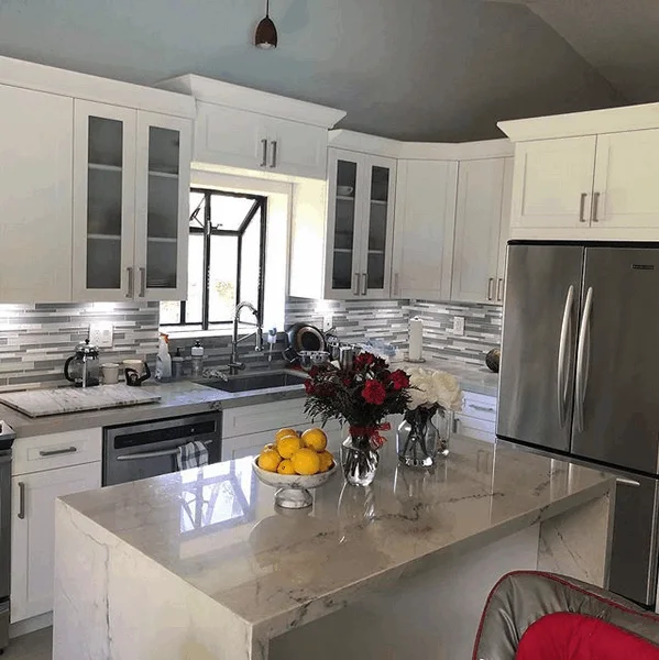 Remodeled kitchen with marble island and white cabinetry